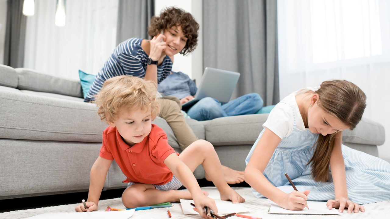 Mom at home working on her laptop with children on the floor - Cyber Security Insurance - TWFG Spring Tx - The Woodlands